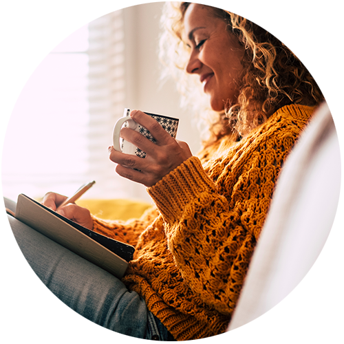 woman drinking coffee while writing